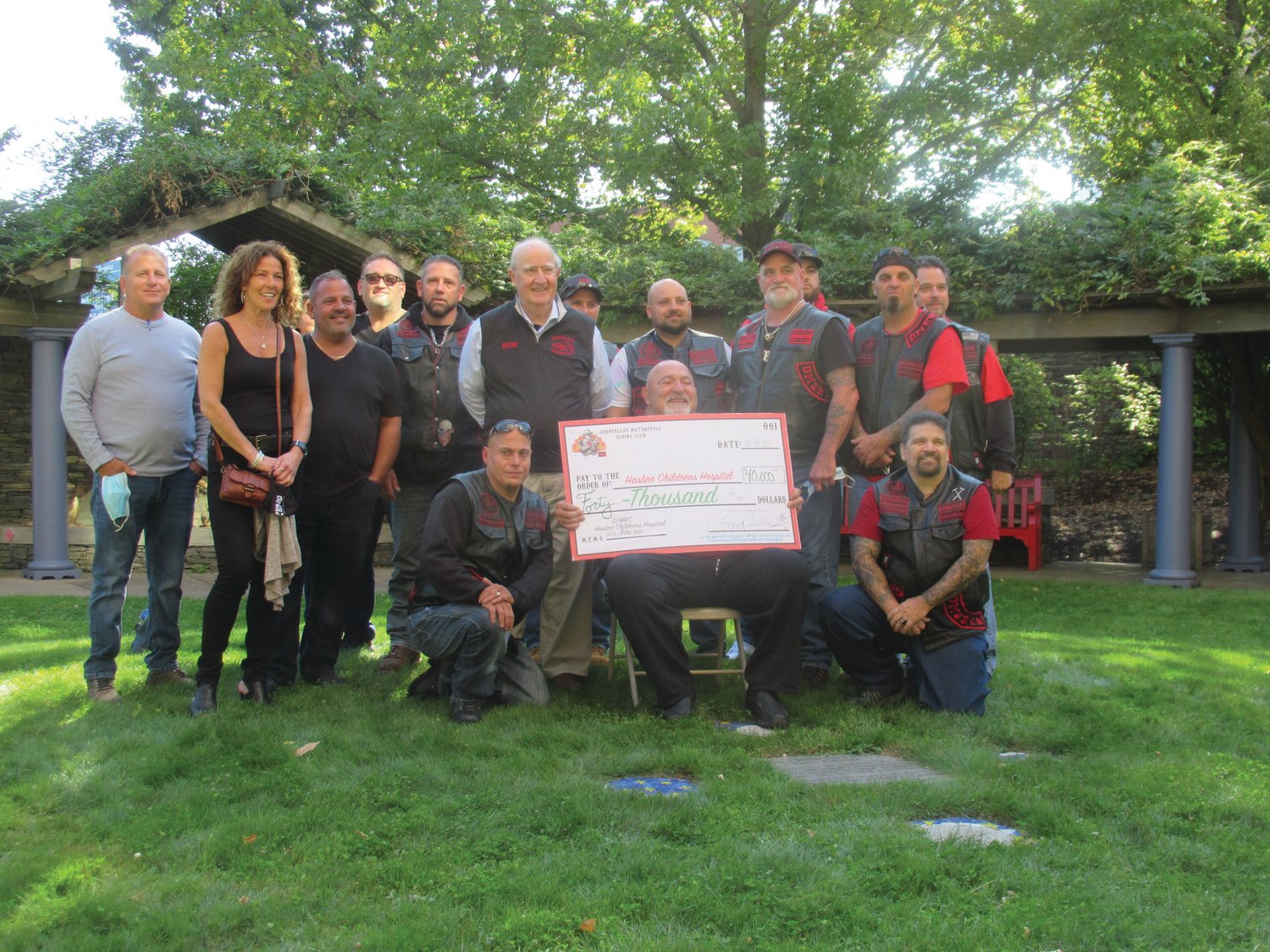 GRAND GROUP: Last year, Goodfellas Motorcycle Club Treasurer Anthony “Cal” Calabro is all smiles as he holds the club’s ceremonial check for $40,000. He’s backed by members and friends inside the Healing Garden at Hasbro Children’s Hospital.
